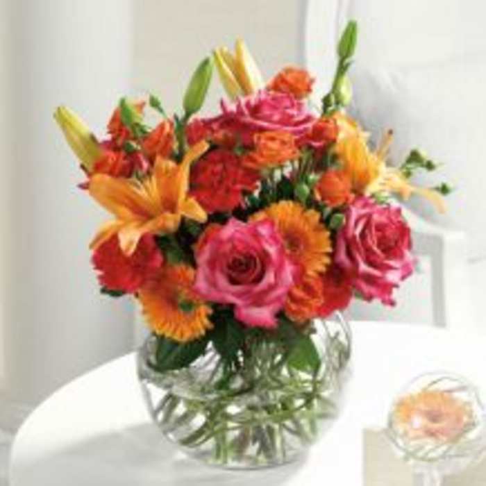 Mixed bouquet of pink roses and orange lilies in a clear glass vase