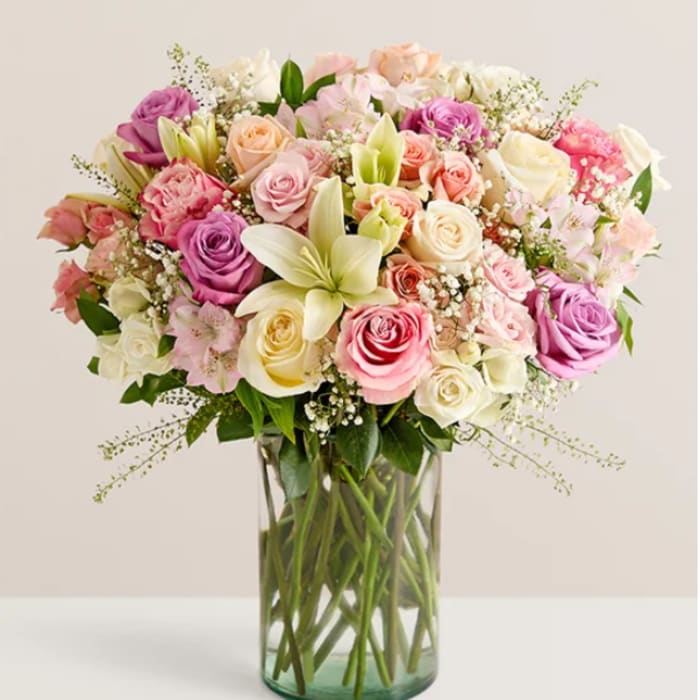 Mixed pink, white, and peach roses in a clear glass vase