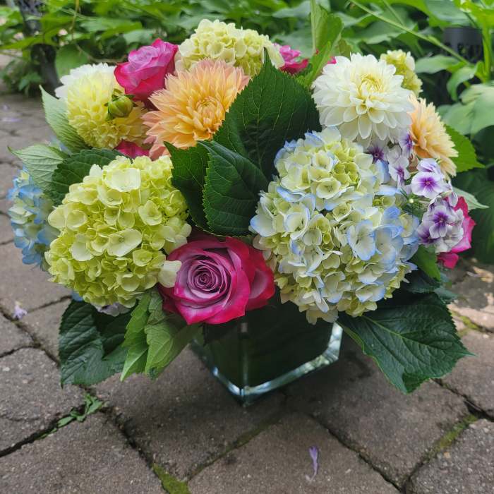 Mixed bouquet of hydrangeas, roses, and dahlias in a glass vase