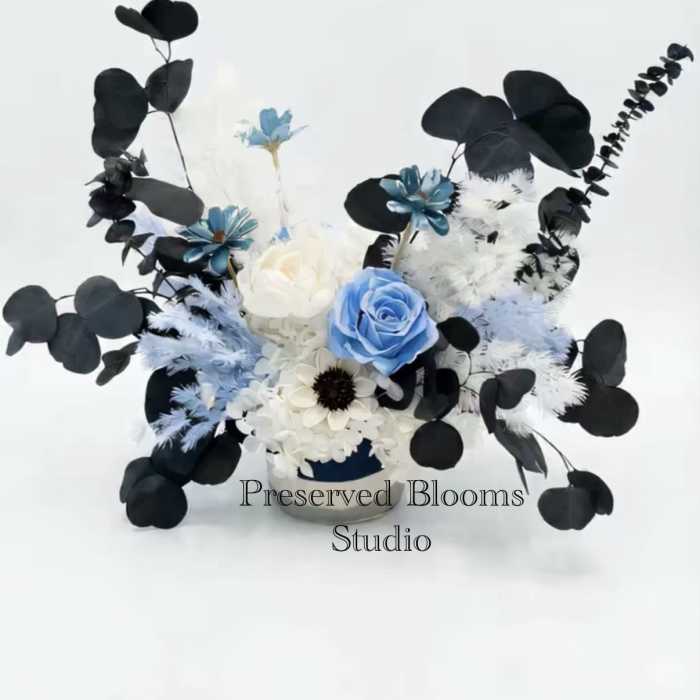 Asymmetrical arrangement of blue and white flowers with black foliage in a low container