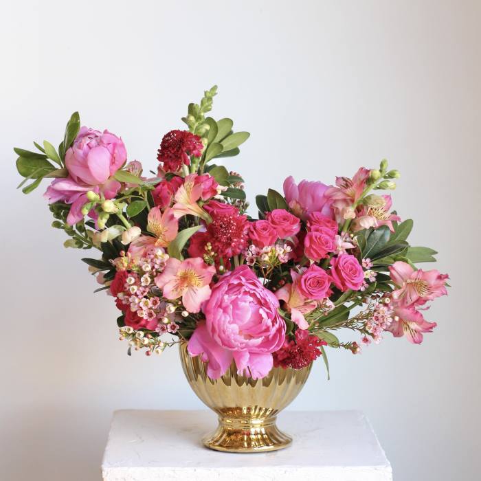 Pink floral arrangement in a gold vase