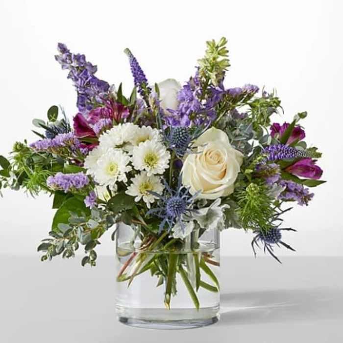 Mixed bouquet of white and purple flowers in a clear glass vase