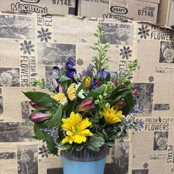 Mixed bouquet in a blue pot with yellow daisies and purple blooms