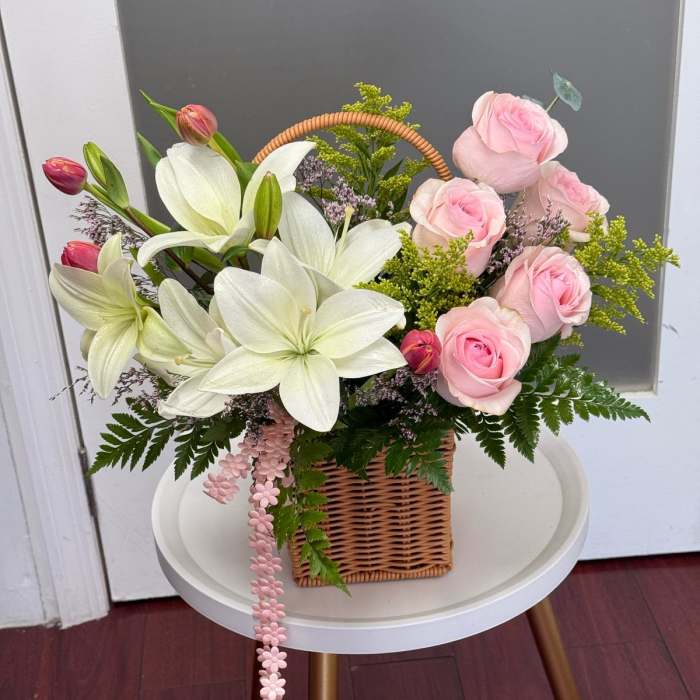Basket arrangement of pink roses and white lilies