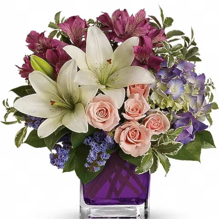Bouquet of white lilies, pink roses, and purple flowers in a purple vase
