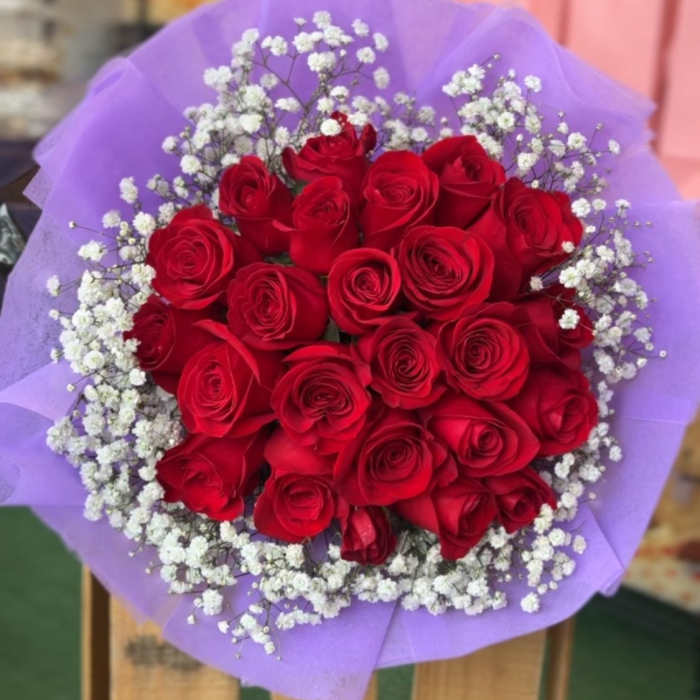 Bouquet of red roses with white baby's breath wrapped in purple paper