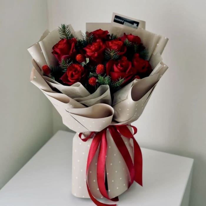 Bouquet of red roses wrapped in beige paper with a red ribbon