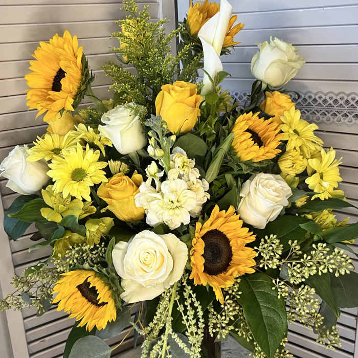 Bouquet of yellow sunflowers and white roses in a glass vase