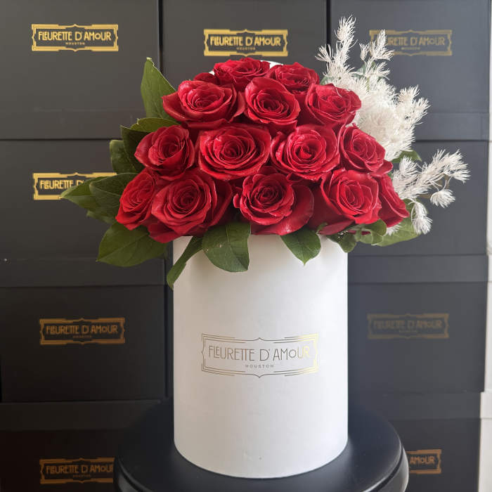 Red roses arranged in a white hat box with white filler flowers
