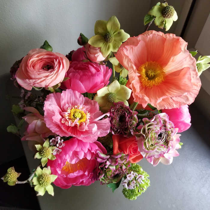 Top view of a bright pink and peach flower arrangement with large poppies and ranunculus