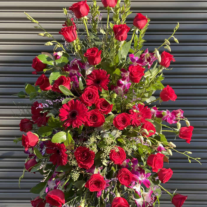 Tall standing spray of red roses and pink orchids on an easel