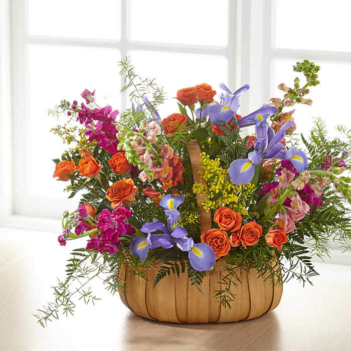 Mixed bouquet with orange roses and purple irises in a woven basket