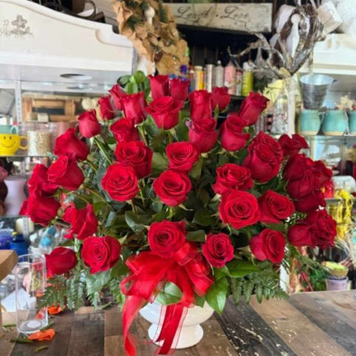 Large bouquet of red roses in a white vase with a red ribbon