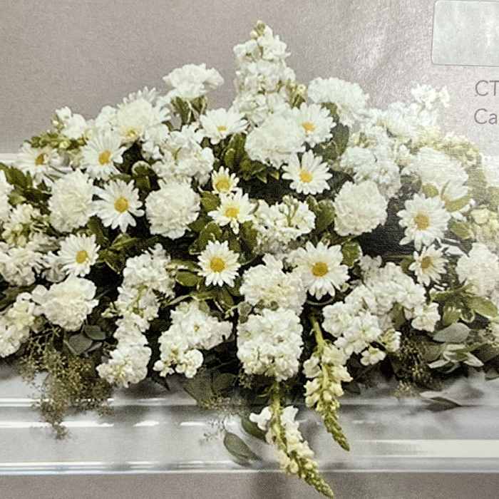 Long white casket spray of daisies and carnations with cascading blooms.