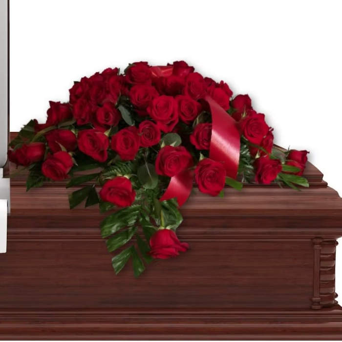 Red rose casket spray with ribbon on a wooden casket