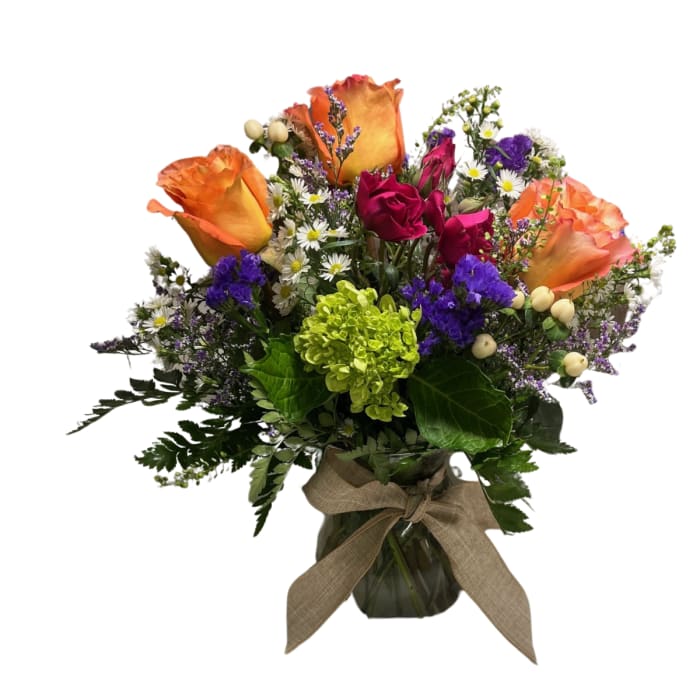Bouquet of orange and pink roses in a glass vase with a ribbon