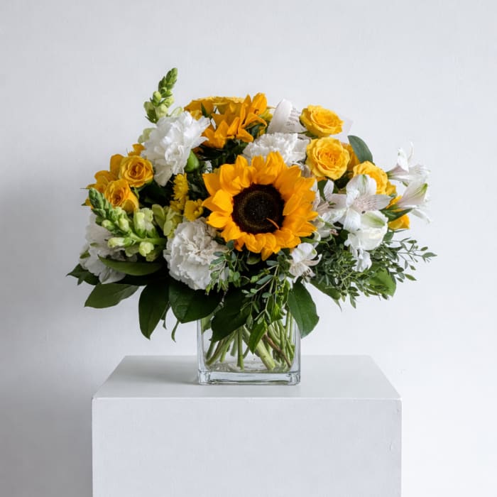 Yellow sunflower bouquet with white and yellow flowers in a clear glass vase