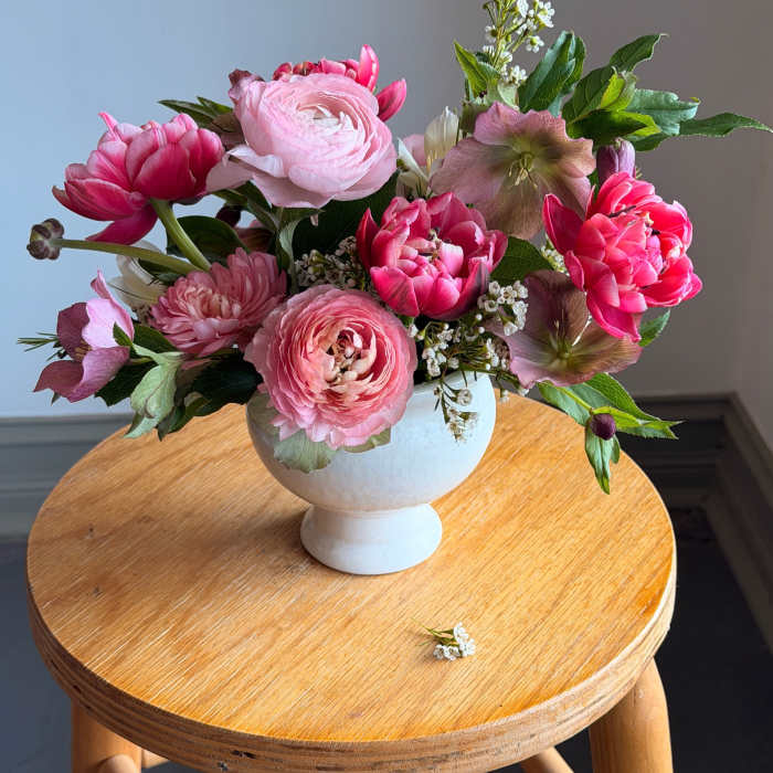 Pink floral arrangement in a white pedestal vase