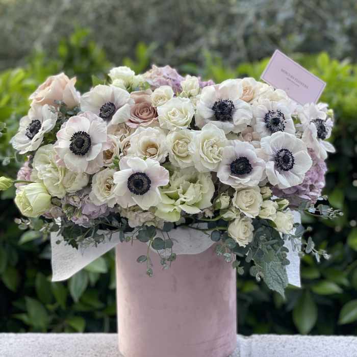 Blush and white floral arrangement in a pink hat box