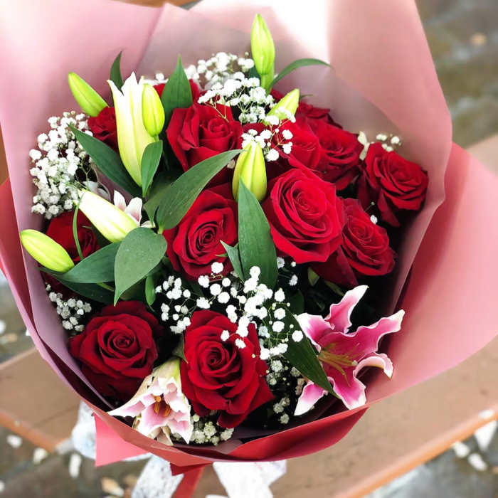 Bouquet of red roses and pink lilies wrapped in pink paper