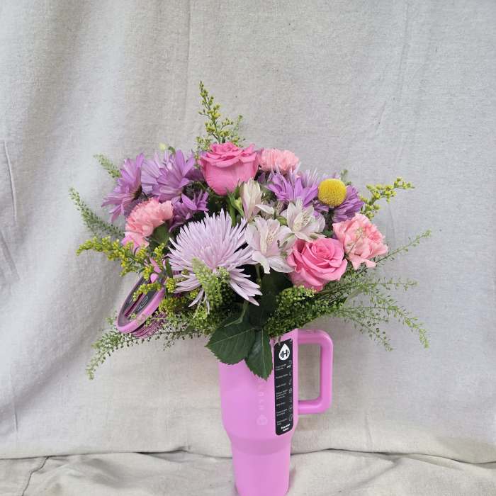 Pink and purple mixed bouquet arranged in a bright pink handled travel tumbler