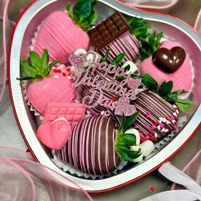 Heart-shaped box of chocolate-covered strawberries with pink decorations