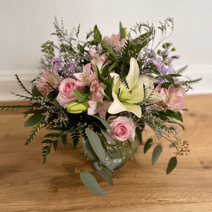 Pink roses and lilies arranged in a glass vase