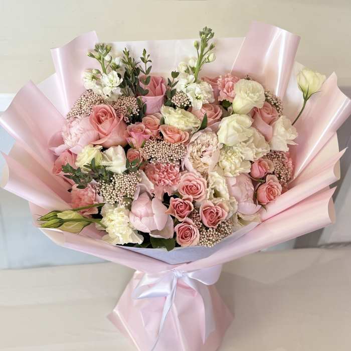 Bouquet of pink and white roses wrapped in pale pink paper
