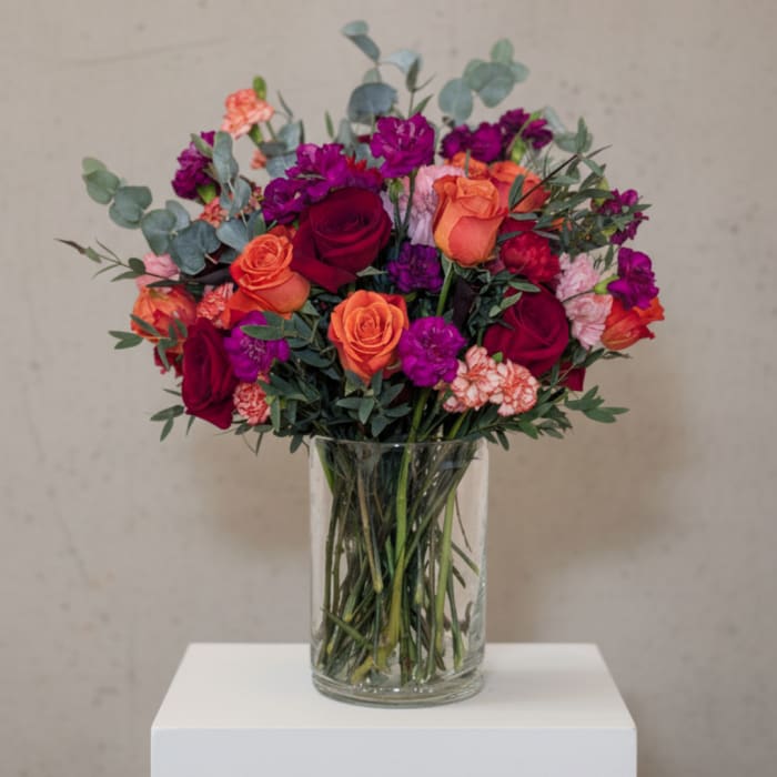Bouquet of red, orange, and purple flowers in a clear glass vase