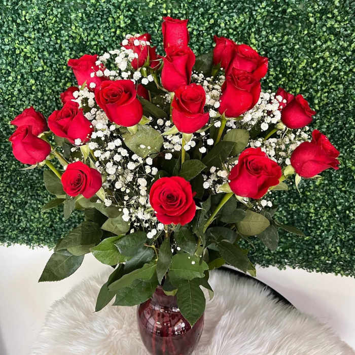 Red roses with white baby's breath in a red glass vase