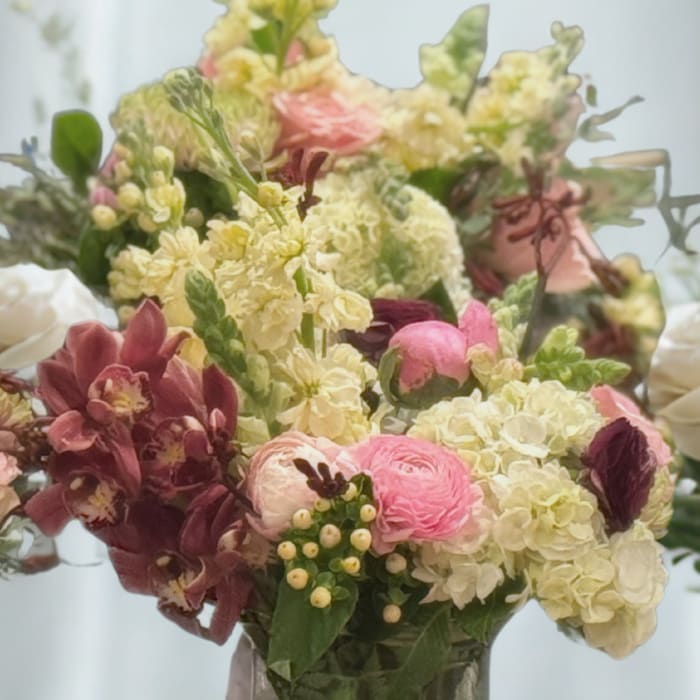 Mixed pink, cream, and burgundy flowers in a glass vase