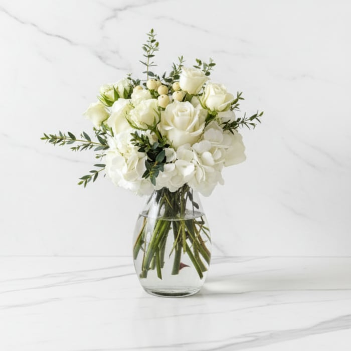 White roses and hydrangeas in a clear glass vase