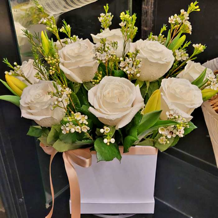 White roses and small white blossoms in a pink gift box