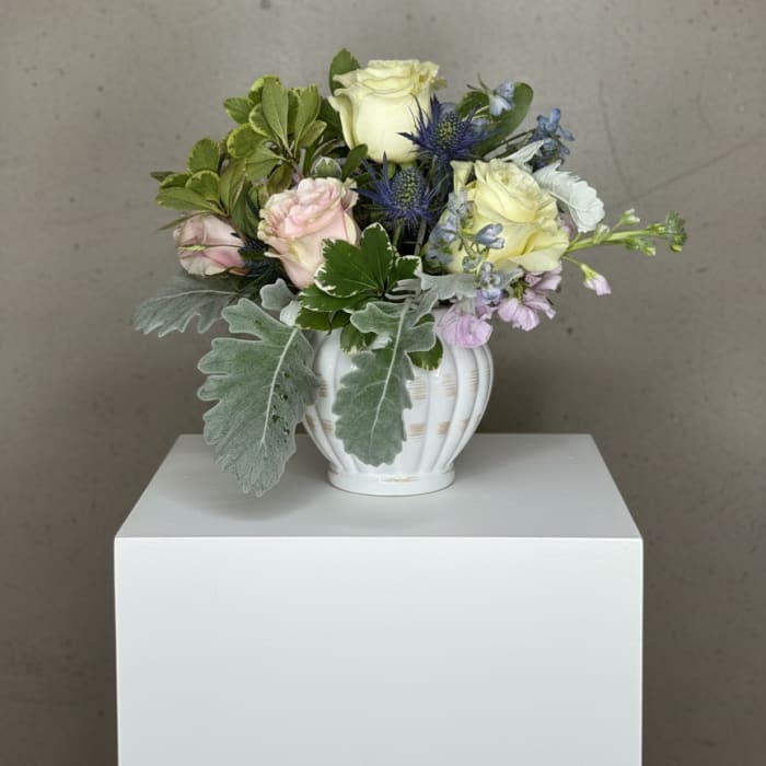 Mixed bouquet in a white vase with pale roses and blue thistle