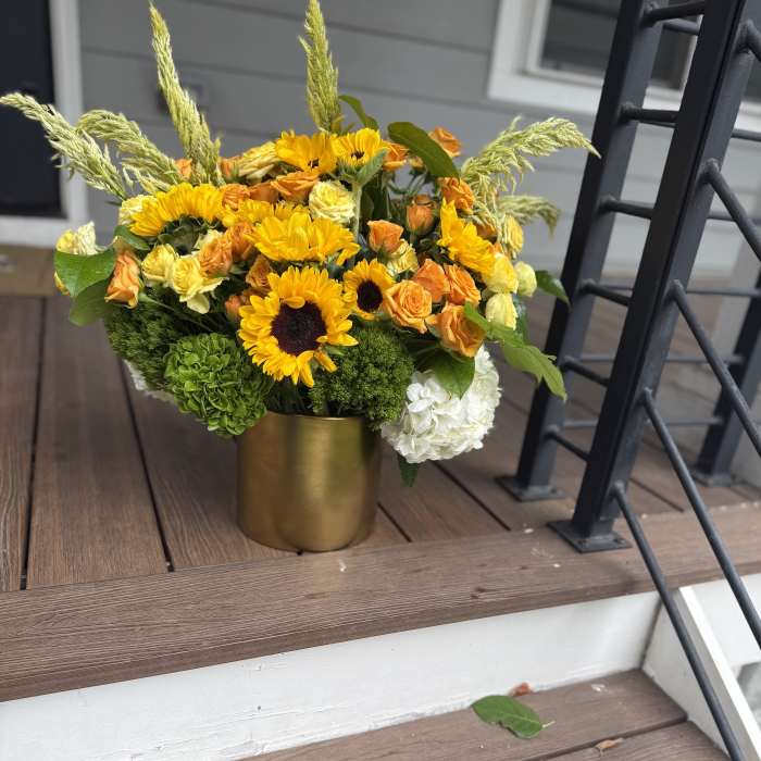 Yellow and orange flowers arranged in a gold vase