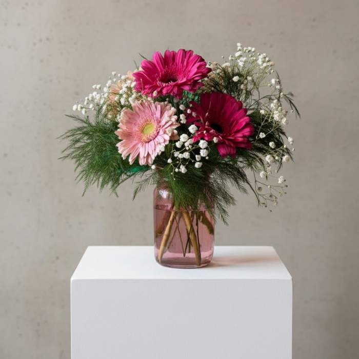 Pink gerbera daisies in a glass vase with baby's breath