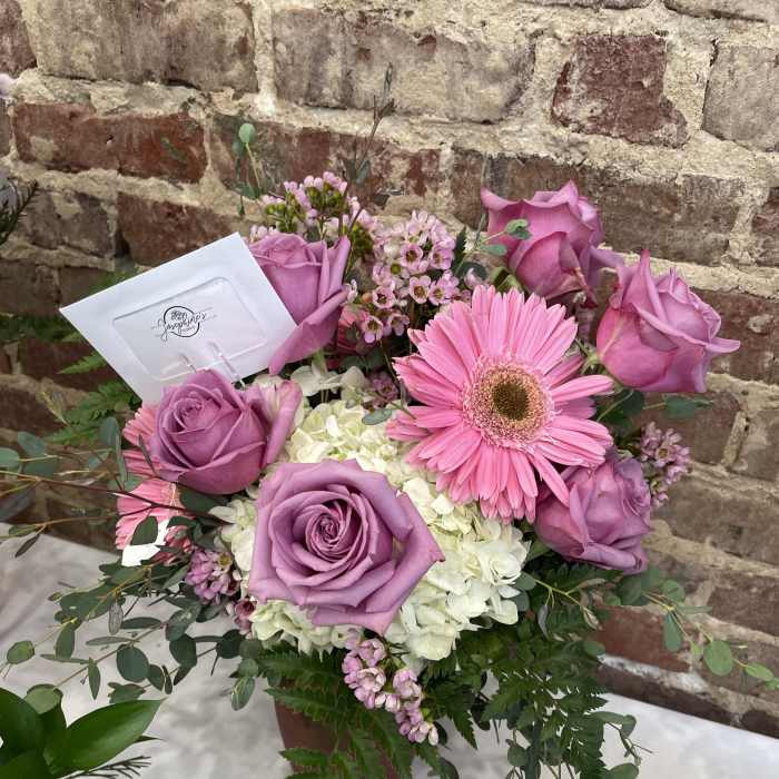 Pink and lavender roses with a pink gerbera daisy in a vase