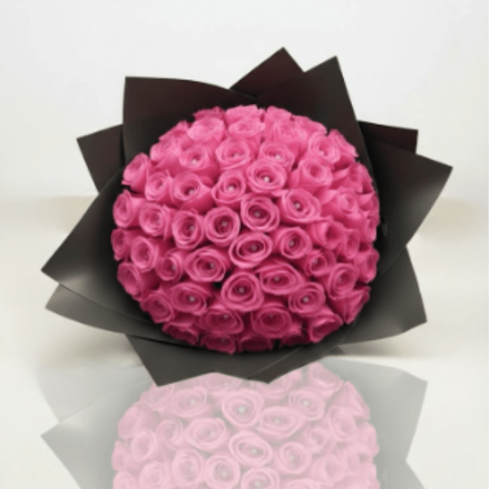 Round bouquet of bright pink roses wrapped in black paper