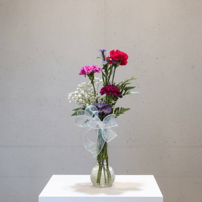 Tall mixed bouquet in a clear glass vase with a sheer ribbon bow