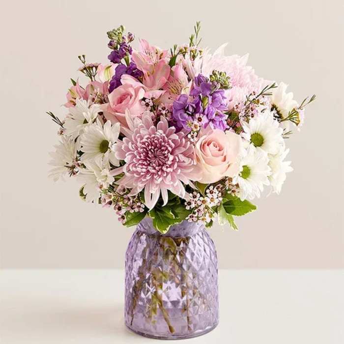 Pink and white mixed bouquet in a purple glass vase