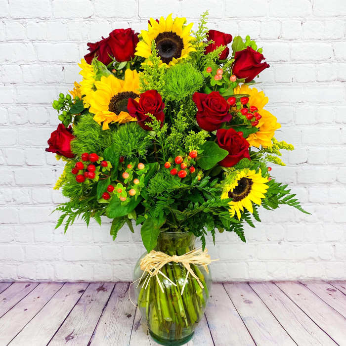 Bouquet of red roses and yellow sunflowers in a glass vase