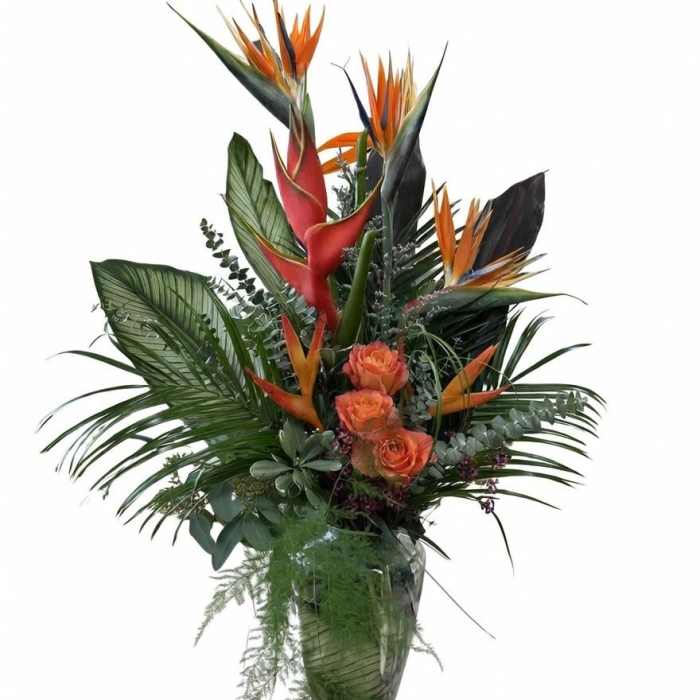 Tropical bouquet with orange bird of paradise and roses in a glass vase