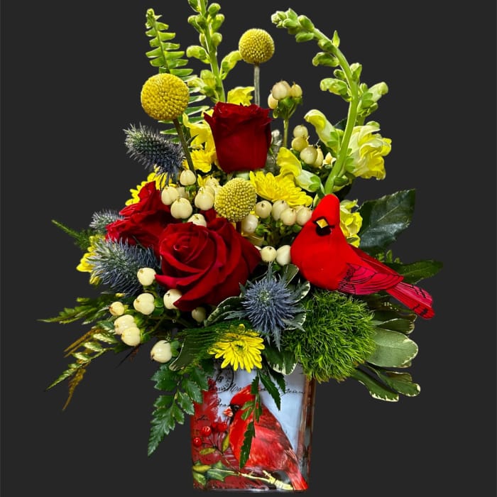 Red roses and yellow flowers in a decorative vase with a red cardinal design