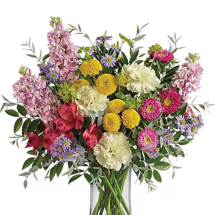 Mixed bouquet of pink, yellow, white, and purple flowers in a glass vase