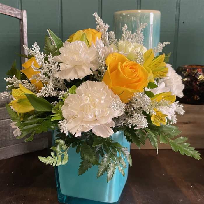 Yellow and white floral arrangement in a blue vase
