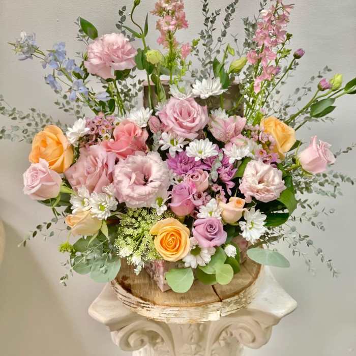 Pastel mixed flower arrangement in a rustic wooden container