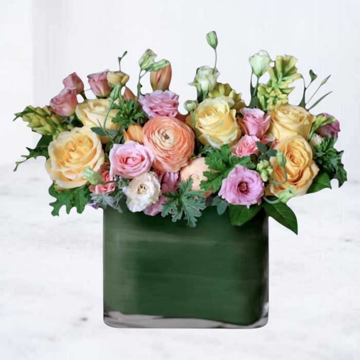 Mixed pastel bouquet in a dark green square vase