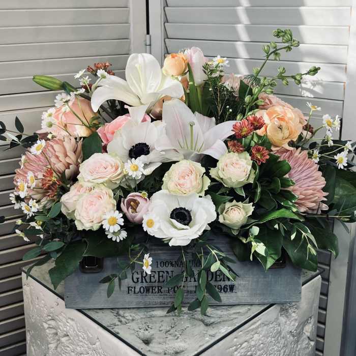Mixed bouquet of pale pink and white flowers in a wooden box