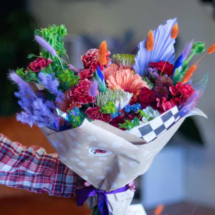 Colorful bouquet with pink, purple, and orange flowers wrapped in paper