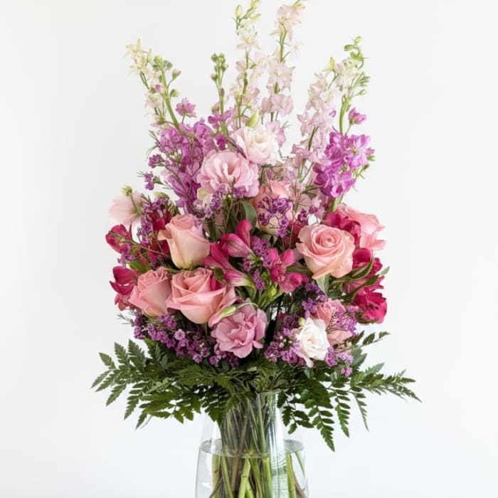Pink and purple mixed flower arrangement in a clear glass vase